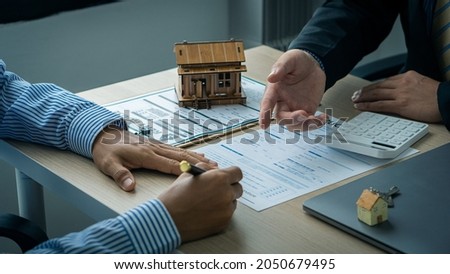 Real estate professionals and clients discussing home purchases, insurance or real estate loans. Home sales agents sit at the office with new homebuyers in the office. Royalty-Free Stock Photo #2050679495