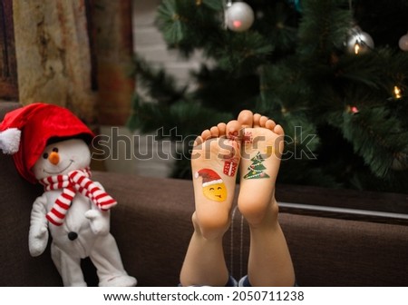 toy snowman and children's bare feet with drawn pictures on the theme of the new year. Christmas celebration concept. positive festive cozy christmas atmosphere