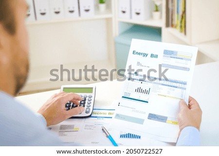 Man calculating electric bill statement and home energy consumption Royalty-Free Stock Photo #2050722527