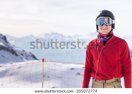 A portrait of a young adult in front of snow mountains ready to ski!