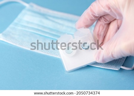 Hard contact lenses in plastic transparent container on a blue background. Myopia astigmatism correction prescription Ophthalmologist hand accessories.