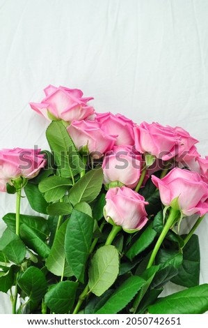 Bouquet of pink roses on the white linens on bed 