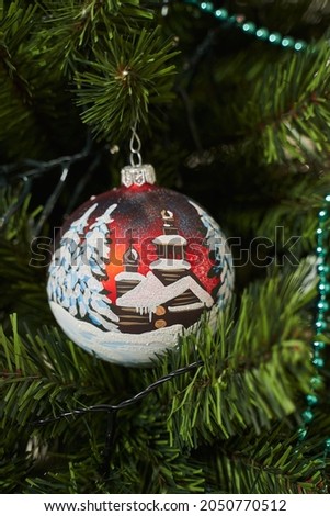 Christmas decoration ball with a painted snow-covered house and fir trees in the snow. christmas decoration on christmas tree
