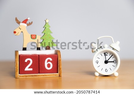 26th December, Christmas day - advent calendar with reindeer. White vintage alarm clock on a wooden table