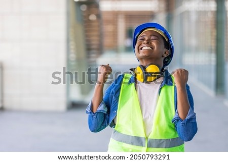 Young african american architect woman wearing security helmet very happy and excited doing winner gesture with arms raised, smiling and screaming for success. Celebration concept.  Royalty-Free Stock Photo #2050793291