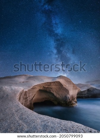Rocks and galaxy. Long exposure. Rocks on the seashore. Stars on the dark sky. Photo as wallpaper. Natural background.