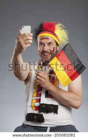 Ecstatic german soccer fan making selfie with smartphone