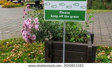 Sign Do Not Walk On The Grass with pink flowers. No Sign Of Trampling The Lawn. Nature concept.
