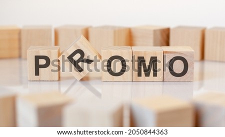 promo - word of wooden blocks with letters on a gray background. Reflection of the caption on the mirrored surface of the table. Selective focus.