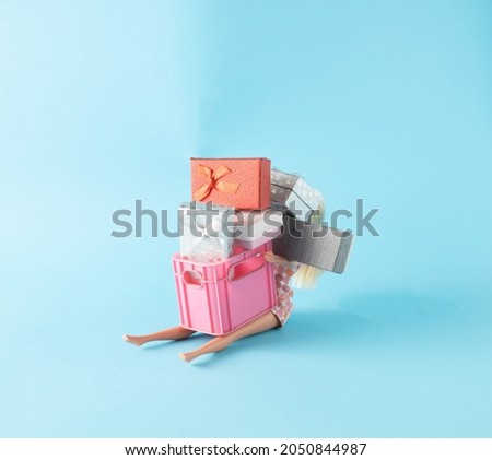 Pink crate with a bunch of presents in girls lap on blue background. Minimal new year concept.