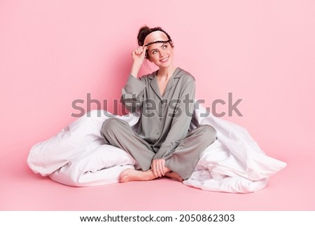 Portrait of attractive dreamy cheerful girl in pajama sitting on bed linen isolated over pink pastel color background Royalty-Free Stock Photo #2050862303