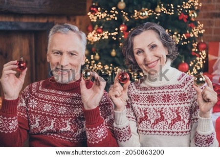 Photo portrait elder couple smiling sitting on floor before xmas decorating xmas tree keeping balls