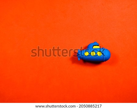 Toy submarine on a red background with copy space.