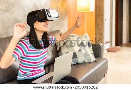 Young asian woman is using virtual reality headset.Concept of virtual reality, simulation, gaming and future technology.Asian woman play game in living room apartment.