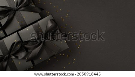 Top view photo of black gift boxes with black ribbon bow tag and golden confetti on isolated black background with blank space Royalty-Free Stock Photo #2050918445