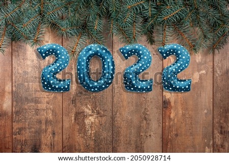 Happy New Year 2022. Foil balloons numbers 2022 on wooden rustic table with branches of Christmas trees. Happy New Year 2022 celebration. Flat lay, top view
