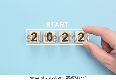 Start 2022 concept. Loading new year 2022 with hand putting wood cube in progress bar. Happy new year 2022. blue background