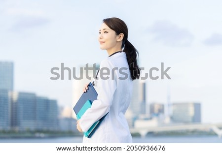 Young asian doctor smiling in front of the city.