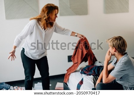 Mother scolding son for messy bedroom Royalty-Free Stock Photo #2050970417