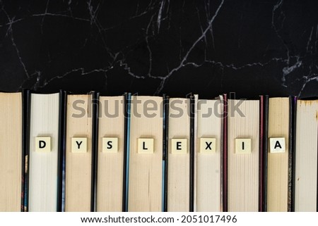 Plastic tiles with letters spelling DYSLEXIA on book. Dyslexia is a reading disorder. Learning concept