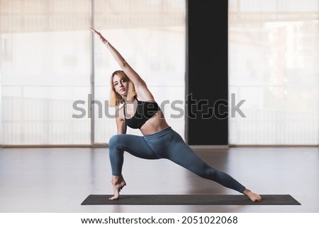 Beautiful young woman practicing yoga by the window of a gym room. Harmony, balance, meditation, relaxation, healthy lifestyle concept Royalty-Free Stock Photo #2051022068