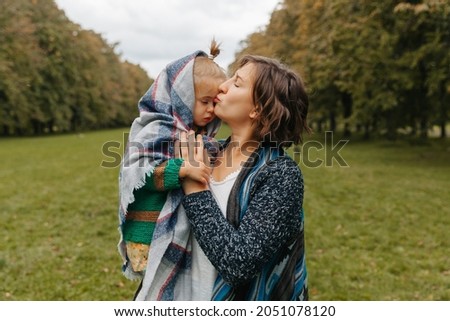 mom holds daughter in her arms in the park. woman with a small child are walking in the autumn park. autumn.