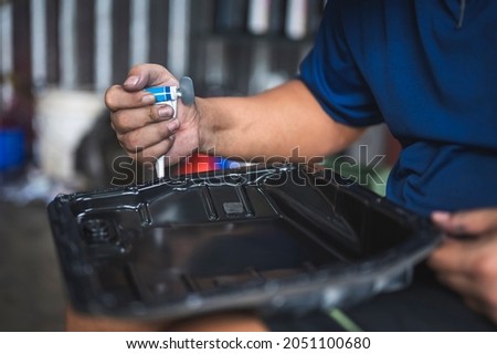 Auto mechanic apply RTV Silicone adhesive to oil pan flange. Royalty-Free Stock Photo #2051100680