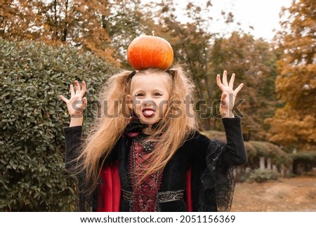 a girl with a pumpkin on her head shows her tongue for Halloween. Sweets or life
