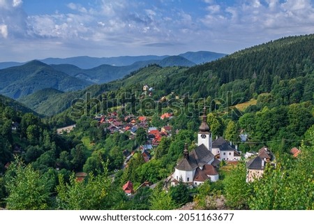 Scenic view of beautiful mountain village – Spania Dolina in Low Tatras, Slovakia. Small church, colorful house roofs and lush forest.  Royalty-Free Stock Photo #2051163677