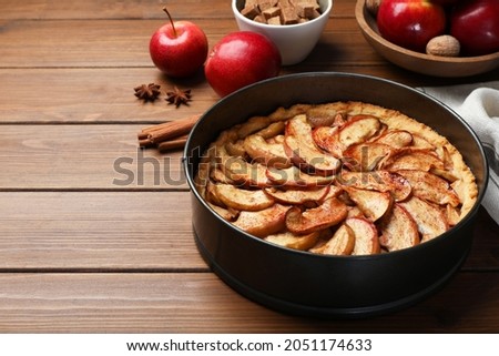 Delicious apple pie and ingredients on wooden table, space for text