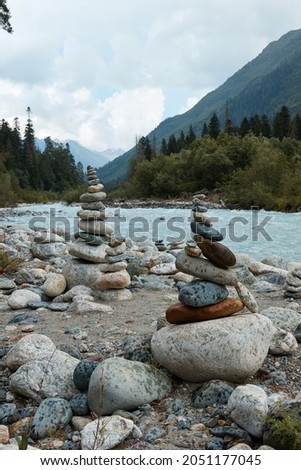 pyramid of stones on the edge of a mountain river, mountains and mountain landscape