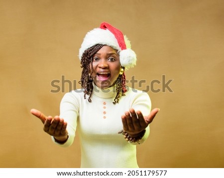 A cute African lady or woman doing beckoning gesture towards the camera and also have a Christmas cap on her head