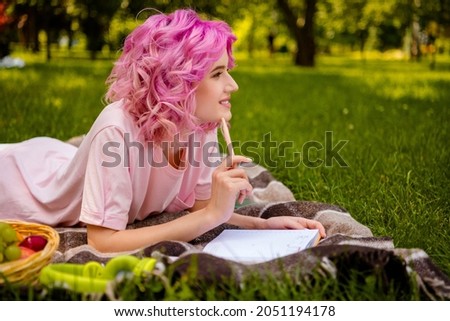 Profile side view portrait of attractive cheerful girl lying on veil grass doing home task work essay in forest outdoors