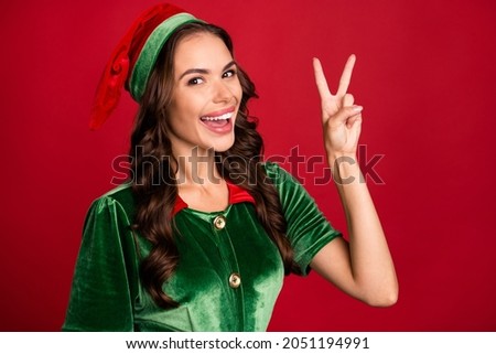 Photo of adorable cute young lady wear green costume showing v-sign smiling isolated red color background