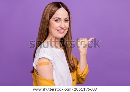 Photo of cute sweet young woman dressed yellow shirt smiling sticky plaster hand pointing empty space isolated purple color background