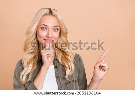Photo of young girl happy positive smile indicate finger empty space promo advise suggest isolated over beige color background