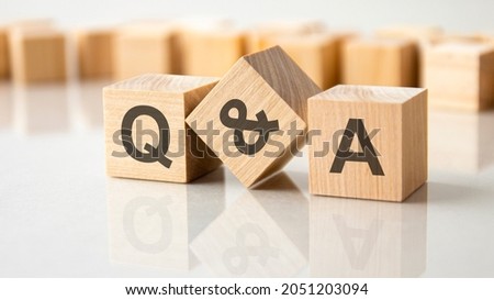 Three wooden cubes with the letters Q and A on the bright surface of a gray table. the inscription on the cubes is reflected from the surface of the table. Q and A - short for question and answer Royalty-Free Stock Photo #2051203094