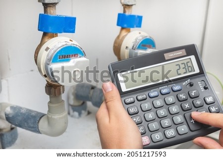 Water meter, concept of rising water prices, man with calculator