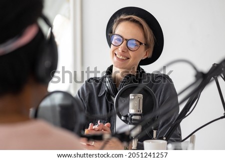 record a podcast and create audio content. An African American woman plays the ukulele in a recording studio or on the radio. a European woman records a music podcast podcast in the studio or in the