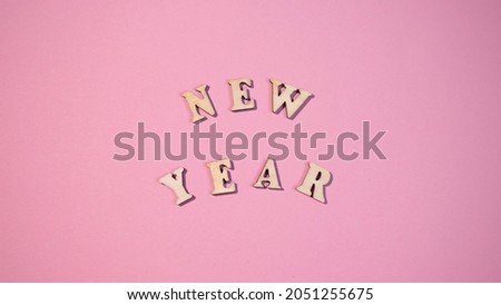 Happy New Year 2022. Quote made from wooden letters on pink background. Creative concept for new year greeting card. Minimalism banner