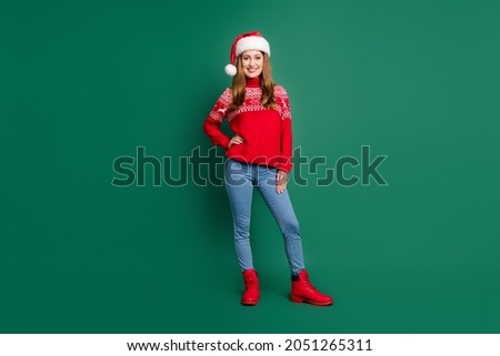 Full length photo of cute young lady stand wear red pullover cap jeans shoes isolated on green color background