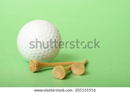 A golf ball and some tees over a green background to compliment the sport.