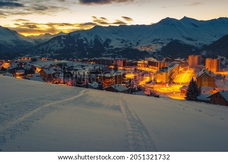 Beautiful alpine winter ski resort with majestic street lights at dawn. Mountain resort and ski slopes at sunrise, La Toussuire, Rhone Alps, France, Europe Royalty-Free Stock Photo #2051321732