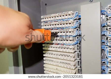 hand punching down circuit panel used for phones. Using a punch down tool punch the wires down into the blades built into the communication circuit for analog phones.  Royalty-Free Stock Photo #2051323181