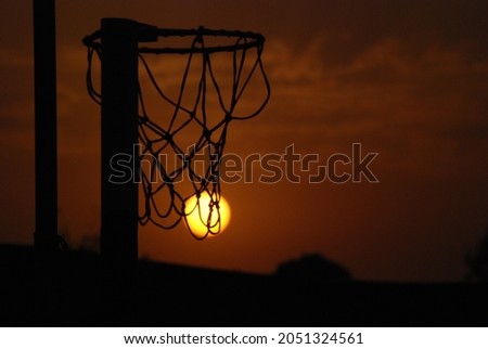 sunset in  a basketball court through the basketball hoop.