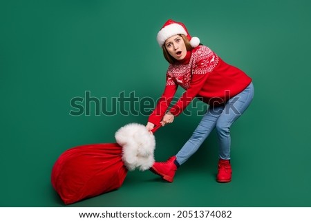 Full body photo of astonished young lady go with bag wear new year pullover cap jeans shoes isolated on green color background