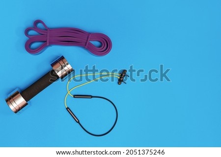 Set of sports accessories massage roller, resistance band, headphones on a yellow background