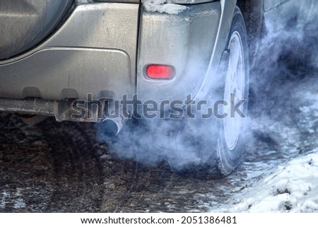 Blue exhaust smoke. Car engine smoking. Smoking exhaust pipe, closeup. Car with gasoline or diesel engine. Engine warming up at idle in winter season Royalty-Free Stock Photo #2051386481