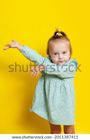 Portrait of a cute baby girl with blue eyes on a yellow background. A place for text. High quality photo