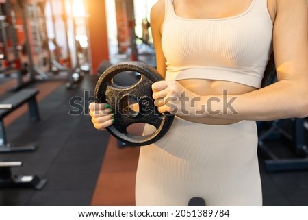 Strong woman holds a disc for a barbell in her hands